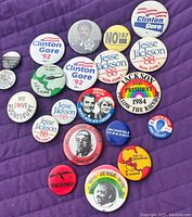 Top view of vintage political campaign button pins including Clinton Gore '92, Jesse Jackson '88, Mondale Ferraro '84 and other related political pinback buttons.