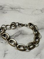 Silver tone metal chain link bracelet laid flat showing the link shape and design.