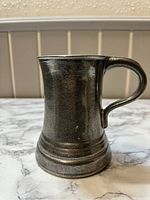 Front angled view of the vintage pewter pint tankard showing the shape, handle, and rings on the base.