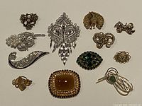 Full collection of 12 vintage pearl and crystal brooches spread out on a flat surface showing varied designs and metal tones.