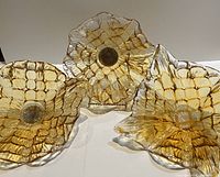 Set of three Murano honeycomb pattern blown glass bowls arranged on white surface, amber honeycomb glass pattern radiating from center, clear glass edges flowing outward.