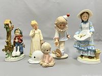 Five porcelain figurines in a group showing children's themes and animals.