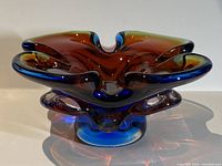 Side view showing freeform shape, colors, and thickness of blown glass ashtray