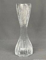 Full front view of the clear crystal vase with vertical ice design and hourglass shape on gray background.