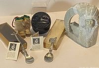 Photo featuring the complete assortment: alabaster carving of indigenous figure by Susie Joe, hematite raven trinket box, two Francis Pollard pewter spoons, and miniature moccasins ornament with fur.