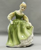 Front view of the Royal Doulton Fair Maiden HN2211 porcelain figurine showing the figure in a green dress holding a hat.