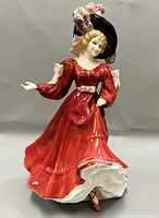 Front view of Royal Doulton Patricia figurine showing red dress and hat with feathers.