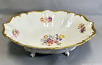 Angled view of the footed bowl showing floral design, scalloped edges, and gold gilding.