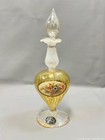 Front view of vintage Murano perfume bottle showing gold tint and floral decoration