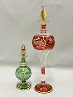 Both vintage Egyptian glass perfume bottles – red and green – showing full height and gold detailing