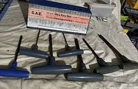 7 T-handle hex keys laid out horizontally on a surface, showing different sizes with blue and black plastic handles and metal shafts