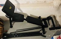 Photo shows a black Everlast adjustable exercise bench partially disassembled, with padded backrest and seat, and steel frame components.