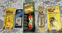 Photo of five new fishing accessories in original packaging including colorful custom components, treble hooks, bright Wing-It float, lipless crankbait lure, and colorful Stick-It jig head.