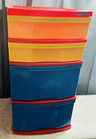 Front view of four drawer plastic organizer with vibrant colored drawers (orange, yellow, blue) and red trim handles, standing upright on wheels.