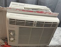 Frigidaire white window air conditioner unit with ventilation grille and control knobs.