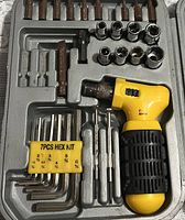 Top view of the yellow and black ratchet screwdriver handle with assorted bits, sockets, and a 7-piece hex key set in a molded plastic case.