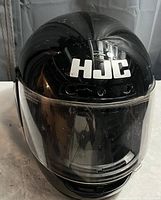 Front view of black HJC FG-tech motorcycle helmet with clear face shield and visible HJC logo.