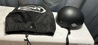 Harley Davidson helmet and black carrying pouch placed side by side on a table