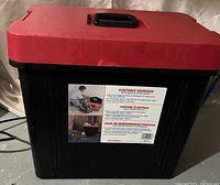 Black portable workbox with red lid and handle, showing exterior with product label.