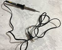 Full soldering iron with black handle, metal tip, and power cord with plug.