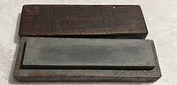 Top view of the sharpening stone inside the open wooden case showing the stone surface and wooden edges.