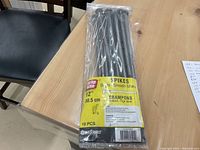 Photo of sealed bag containing 10 Griprite bright smooth shank 12 inch spikes on a wooden surface
