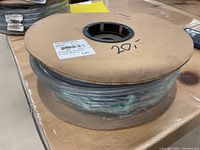 Gray rubber hose coiled on cardboard reel with visible labels showing part number PSVTR 75-100B and length 100 ft.