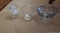 Wide shot of all three etched glass bowls or vases on carpet.