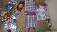 Bead organizer case with multiple small compartments with assorted beads and packaging around it