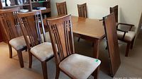 Dining table base with leaf attached and six chairs arranged