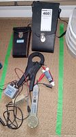 Various electrical testers and two carrying cases arranged on carpet.