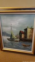 Framed oil painting showing sailing ship in port, buildings, and rowboats. Visible paint texture and cracks on canvas.