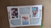 White multi-photo frame containing six photo openings with cardboard protective corners, placed on carpet.