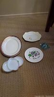Four platters and a milk glass bowl arranged on carpeted floor.