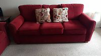Full front view of red La-Z-Boy sofa bed with two patterned throw pillows