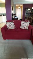 Front view of red two-seat sofa with two patterned cushions