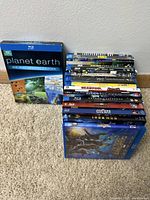Blu-ray discs stacked on carpeted floor showing all titles with visible cover art.