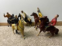 Six Hartland Plastics horse and rider figures arranged on floor and against wall showing variety of figures and horses.