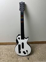 Front view of the Guitar Hero Gibson Les Paul wireless controller for Nintendo Wii. Shows black and white color scheme and colored fret buttons.