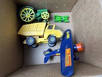 Box containing four vintage metal toys including Tonka dump truck, John Deere tractor, diecast airplane, and small green tractor.