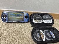 Sony PSP gaming console with SOCOM Fireteam Bravo game displayed on screen alongside zippered carrying case holding game discs.