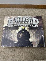 Closed game box showing Railroad Tycoon The Board Game cover art with a steam engine image.
