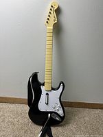 Front view of black Fender Stratocaster style wireless guitar controller with cream neck and white pickguard for Nintendo Wii Rock Band