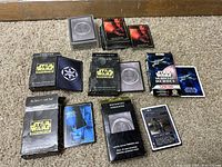 Star Wars card games and packs arranged on floor, showing multiple starter kits, expansion packs, and card stacks with various Star Wars artwork.