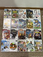 Photo showing all 21 Wii game cases arranged on the floor to identify titles and condition.
