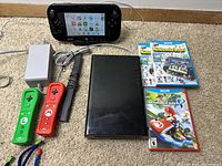 Image showing the Wii U console, GamePad, power adapter, sensor bar, Mario and Luigi themed Wii Remote controllers, and three Wii U game cases including Mario Kart 8.
