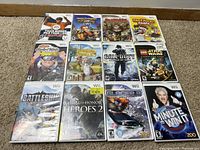 Photo showing 12 Nintendo Wii video game cases arranged in 3 rows of 4 games each on carpet.