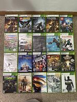 Photo of 20 Xbox 360 game cases laid out on the floor against a wall, showing clear titles and cover art for identification.