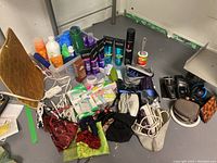 Wide shot of assorted hair care products, personal hygiene items, multiple small cosmetic bags, and electrical cords on the floor.
