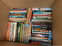 Top-down photo showing a large box filled with paperback sci-fi books arranged spines and covers visible, featuring multiple copies of James White books in the Sector General series, and other sci-fi titles by various authors.